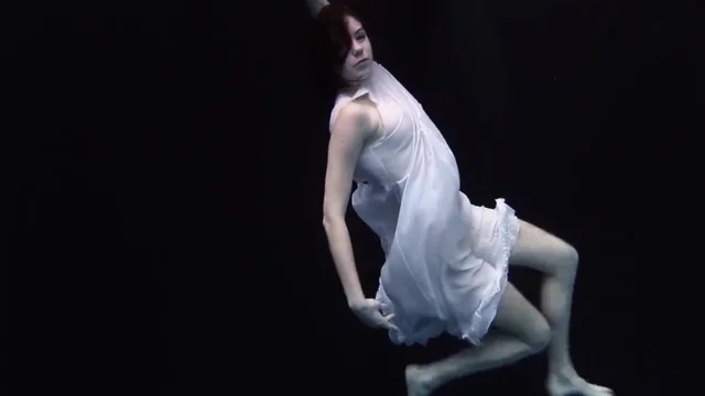 Молоденькая девушка в платье купается в бассейне